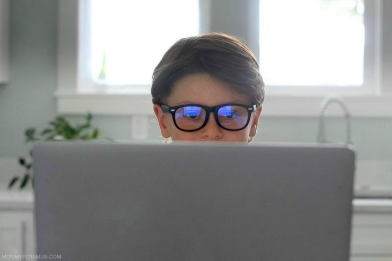 a kid using laptop while wearing blue light blocking glasses